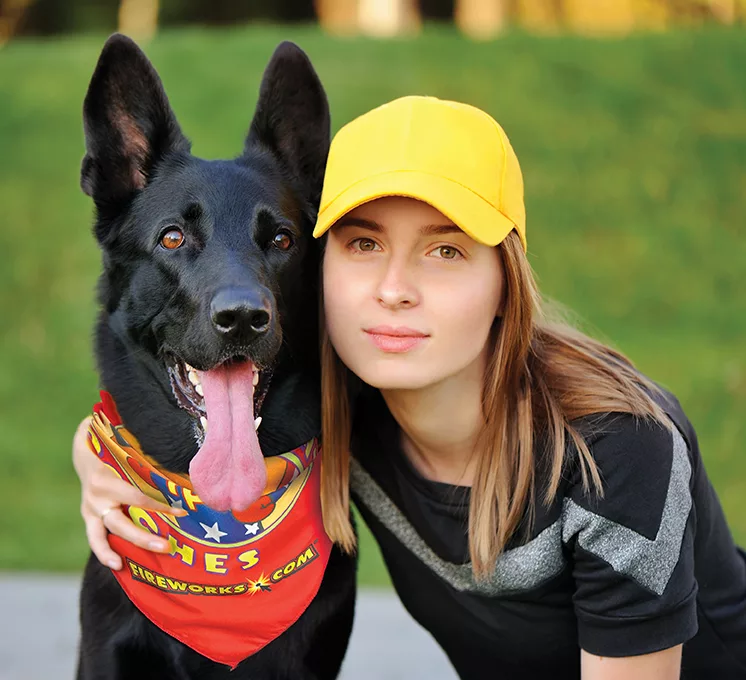 girl with arm around black dog, dog wearing pet bandanna